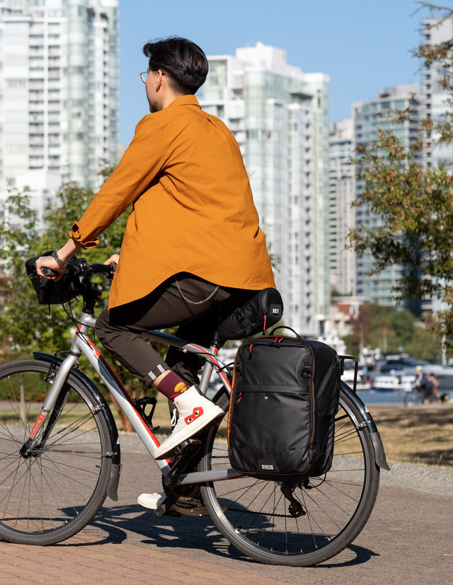 Man riding bicycle with two wheel gear pannier backpack